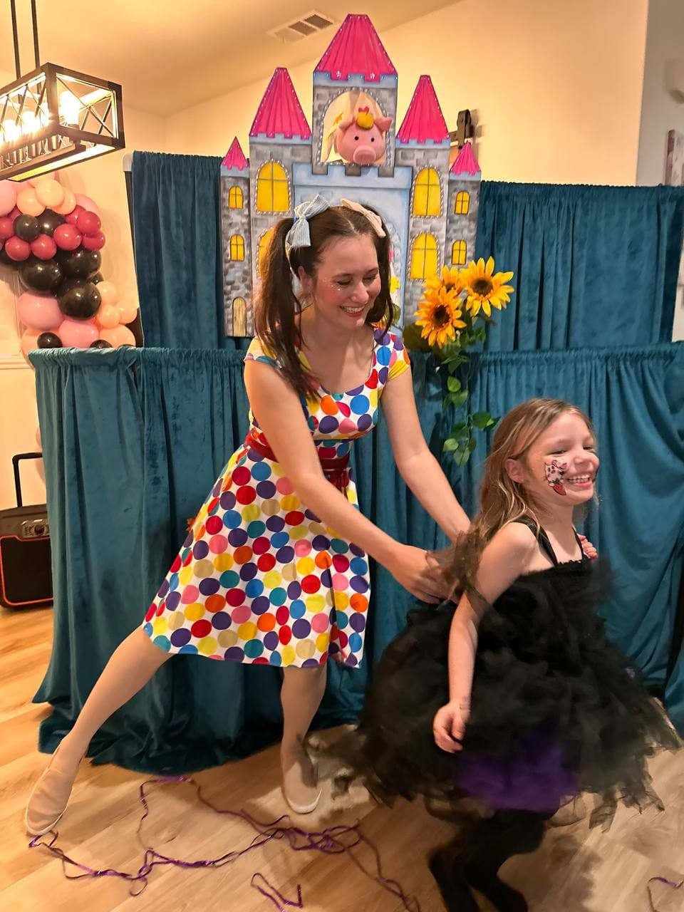 A costumed performer spins and dances with a giggling girl at an indoor party.