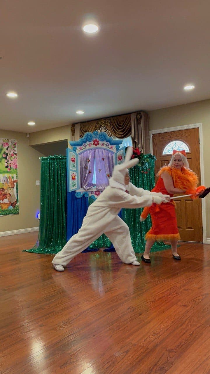A bunny and a fox character act out a playful chase scene on stage.